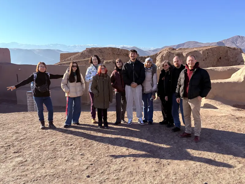 A tour group at an ancient fortress with mountains behind