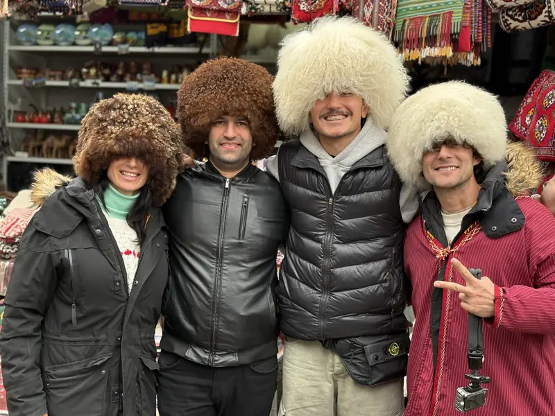 Travelers trying on Turkmen telpek fur hats